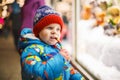 Adorable little boy looking through the window at Christmas decoration in the shop Royalty Free Stock Photo