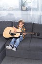 adorable little boy playing guitar on couch