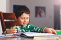 Adorable little boy reading book before going to sleep. Happy kid dressed in pajamas reads a story and amuses himself. Cute boy l Royalty Free Stock Photo