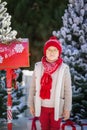 Adorable little boy with red hat and green glasses sending her letter to Santa, Christmas time Royalty Free Stock Photo