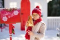 Adorable little boy with red hat and green glasses sending her letter to Santa, Christmas time Royalty Free Stock Photo