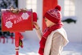 Adorable little boy with red hat and green glasses sending her letter to Santa, Christmas time Royalty Free Stock Photo