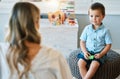 An adorable little boy sitting in his bedroom at home and talking to his mother. Happy male child bonding with his mom Royalty Free Stock Photo