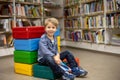 Adorable little boy, sitting in library, reading book and choosing what to lend, kid in book store Royalty Free Stock Photo