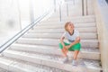 Adorable little boy sitting on stairs in a city Royalty Free Stock Photo