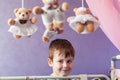 Adorable little boy standing near cot with Baby music mobile carousel. Big Brother watches younger sister in crib