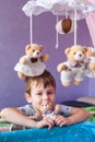 Adorable little boy standing near cot with Baby music mobile carousel. Big Brother watches younger sister in crib