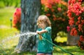 Adorable little boy is watering the plant outside the house, concept of plant growing learning activity for kid and Royalty Free Stock Photo