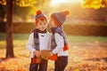 Adorable little brothers with teddy bear in park on autumn day