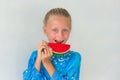 Adorable little caucasian child girl with blue eyes in a blue dress Eating Watermelon isolated on White Background. Concept of