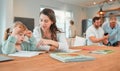 Adorable little caucasian girl sitting at table and doing homework while her mother helps her. Beautiful serious young Royalty Free Stock Photo