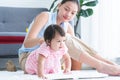 Adorable little Caucasian 7 months newborn baby crawling on floor, playing near mom at home. Asian young mother looking and taking