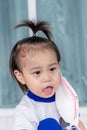 Adorable little child girl with big capillary strawberry hemangiomas red birthmark on head refuses to wear medical face mask that