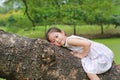 Adorable little child girl climb and resting on big tree trunk in the garden outdoor Royalty Free Stock Photo