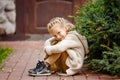 Adorable little curly blond girl in beige knitted sweater smiles