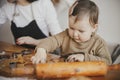 Adorable little daughter with mother making together christmas gingerbread cookies on messy wooden table. Cute toddler girl helps Royalty Free Stock Photo