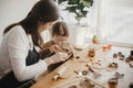 Adorable little daughter with mother making together christmas gingerbread cookies on messy wooden table. Cute toddler girl helps Royalty Free Stock Photo