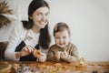 Adorable little daughter with mother making together christmas gingerbread cookies on messy wooden table. Cute toddler girl helps Royalty Free Stock Photo