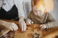 Adorable little daughter and mother making together gingerbread cookies on messy wooden table in modern room. Cute toddler girl Royalty Free Stock Photo