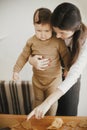 Adorable little daughter and mother making together gingerbread cookies on messy wooden table in modern room. Cute toddler girl Royalty Free Stock Photo