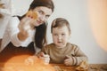 Adorable little daughter and mother making together gingerbread cookies on messy wooden table in modern room. Cute toddler girl Royalty Free Stock Photo
