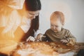 Adorable little daughter and mother making together gingerbread cookies on messy wooden table in modern room. Cute toddler girl Royalty Free Stock Photo