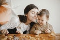 Adorable little daughter and mother making together gingerbread cookies on messy wooden table in modern room. Cute toddler girl Royalty Free Stock Photo