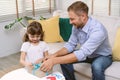 Adorable little daughter sitting on floor opening a gift box. Single Father helping his daughter opening a gift box at home. Royalty Free Stock Photo