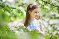 Adorable little girl in blooming apple tree garden on spring day