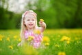 Adorable little girl in blooming dandelion meadow on beautiful spring day Royalty Free Stock Photo