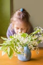 Adorable little girl with bouquet of bird cherry branches with fragrant white flowers.