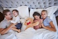 Adorable little girl and boy laughing and having fun while their parents tickle and tease them in bed. Loving parents Royalty Free Stock Photo