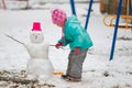 Adorable little girl building a snowman on a snowy winter day. Royalty Free Stock Photo