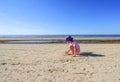 Adorable little girl playing with sand on the beach of Baltic sea. Royalty Free Stock Photo