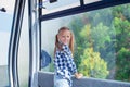 Adorable happy little girl in the cabin on the cable car in mountains in the background of beautful landscape Royalty Free Stock Photo