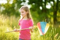 Adorable little girl catching butterflies and bugs with her scoop-net. Child exploring nature on sunny summer day Royalty Free Stock Photo