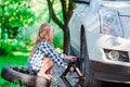 Adorable little girl changing a car wheel outdoors on beautiful summer day Royalty Free Stock Photo