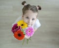 Adorable little girl with cute smile and face expression holding bouquet of pink, purple, yellow, orange gerbera daisies Royalty Free Stock Photo