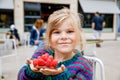 Adorable little girl and delicious raspberry cake. Preschool child eating sweet dessert in French outdoor cafe. Royalty Free Stock Photo