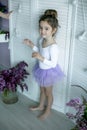 Adorable little girl dressed as a ballerina in a tutu, tying her ballet slippers. Royalty Free Stock Photo