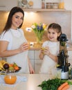 Adorable little girl drink fresh juice with her mom at home. Two females in apron. Fruits and vegetables. Homemade vegan Royalty Free Stock Photo