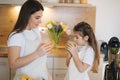 Adorable little girl drink fresh juice with her mom at home. Two females in apron. Fruits and vegetables. Homemade vegan Royalty Free Stock Photo