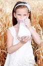 Adorable little girl drinking milk on field of wheat Royalty Free Stock Photo