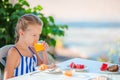 Adorable little girl drinking orange juice on breakfast with sea view Royalty Free Stock Photo