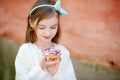 Adorable little girl eating fresh sweet strawberry cake outdoors on warm and sunny summer day Royalty Free Stock Photo