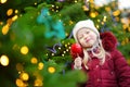 Adorable little girl eating red apple covered with sugar icing on traditional Christmas market. Royalty Free Stock Photo