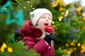 Adorable little girl eating red apple covered with sugar icing on traditional Christmas market. Royalty Free Stock Photo