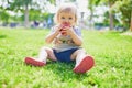 Adorable little girl eating red apple outdoors in park on a sunny day Royalty Free Stock Photo