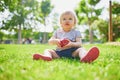 Adorable little girl eating red apple outdoors in park on a sunny day Royalty Free Stock Photo