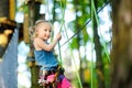 Adorable little girl enjoying her time in climbing adventure park on warm and sunny summer day Royalty Free Stock Photo